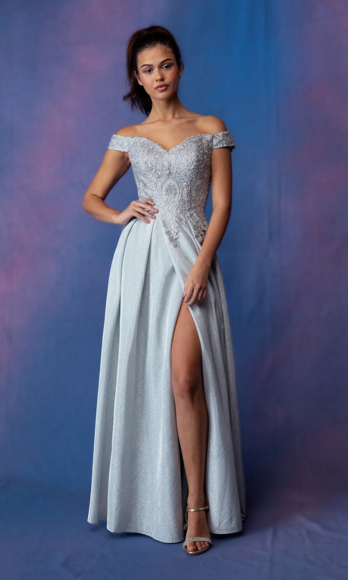 A woman wearing the Long Prom Dress: Eureka 9806, a silver off-the-shoulder gown with lace applique and a thigh-high slit, stands against a blue and purple backdrop.